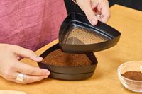 A person sifts coffee beans ground using the OXO Brew Conical Burr Coffee Grinder