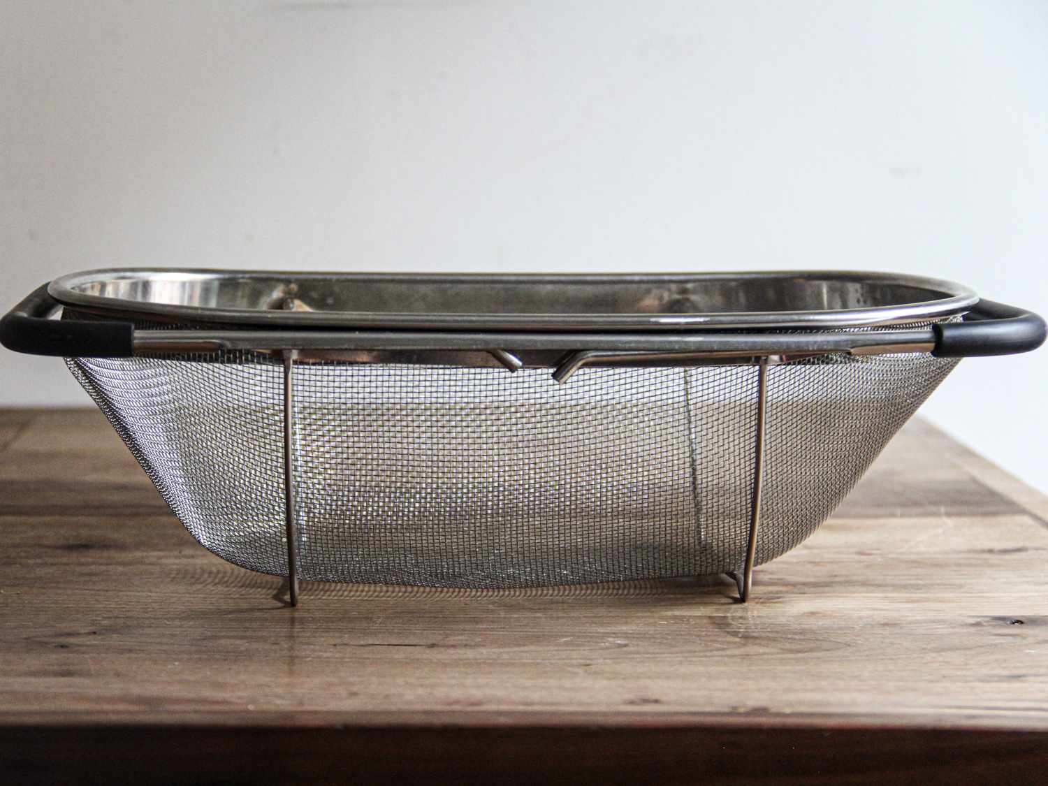 A closeup look at the US Kitchen Supply colander on a wooden surface