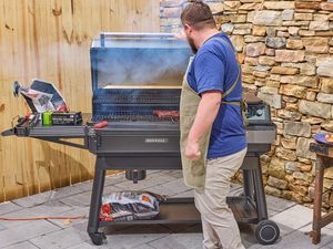 Person grilling meat on a large barbecue grill outdoors