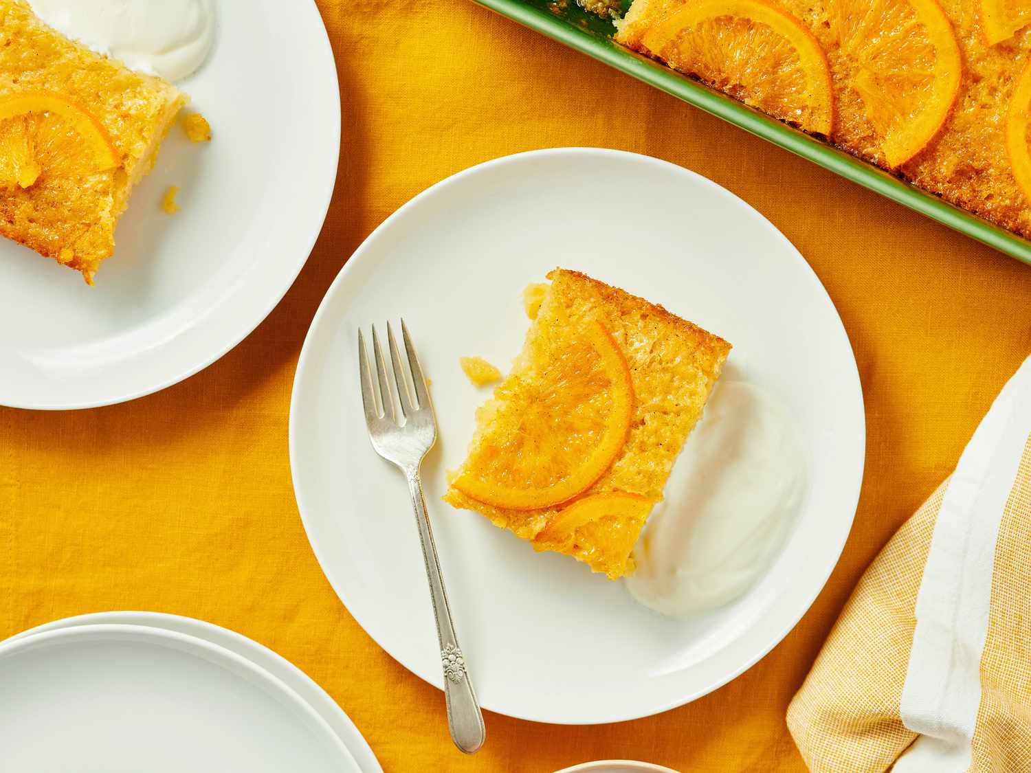 Plates with sliced cake garnished with orange, accompanied by a dollop of yogurt