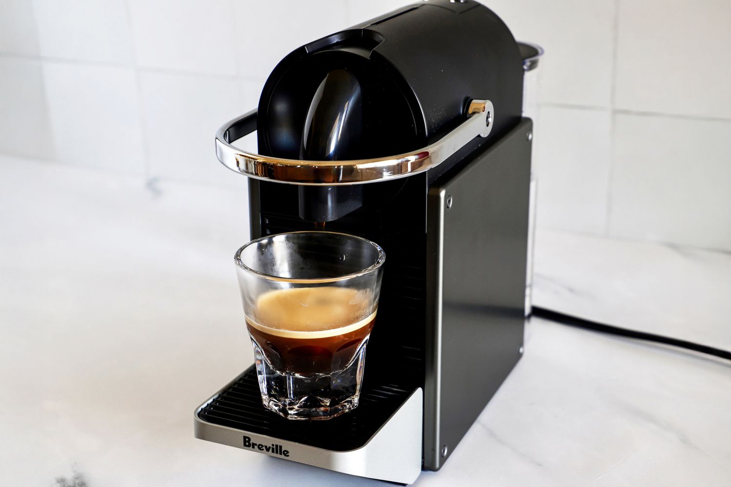 A singleserve coffee machine brewing espresso into a glass cup