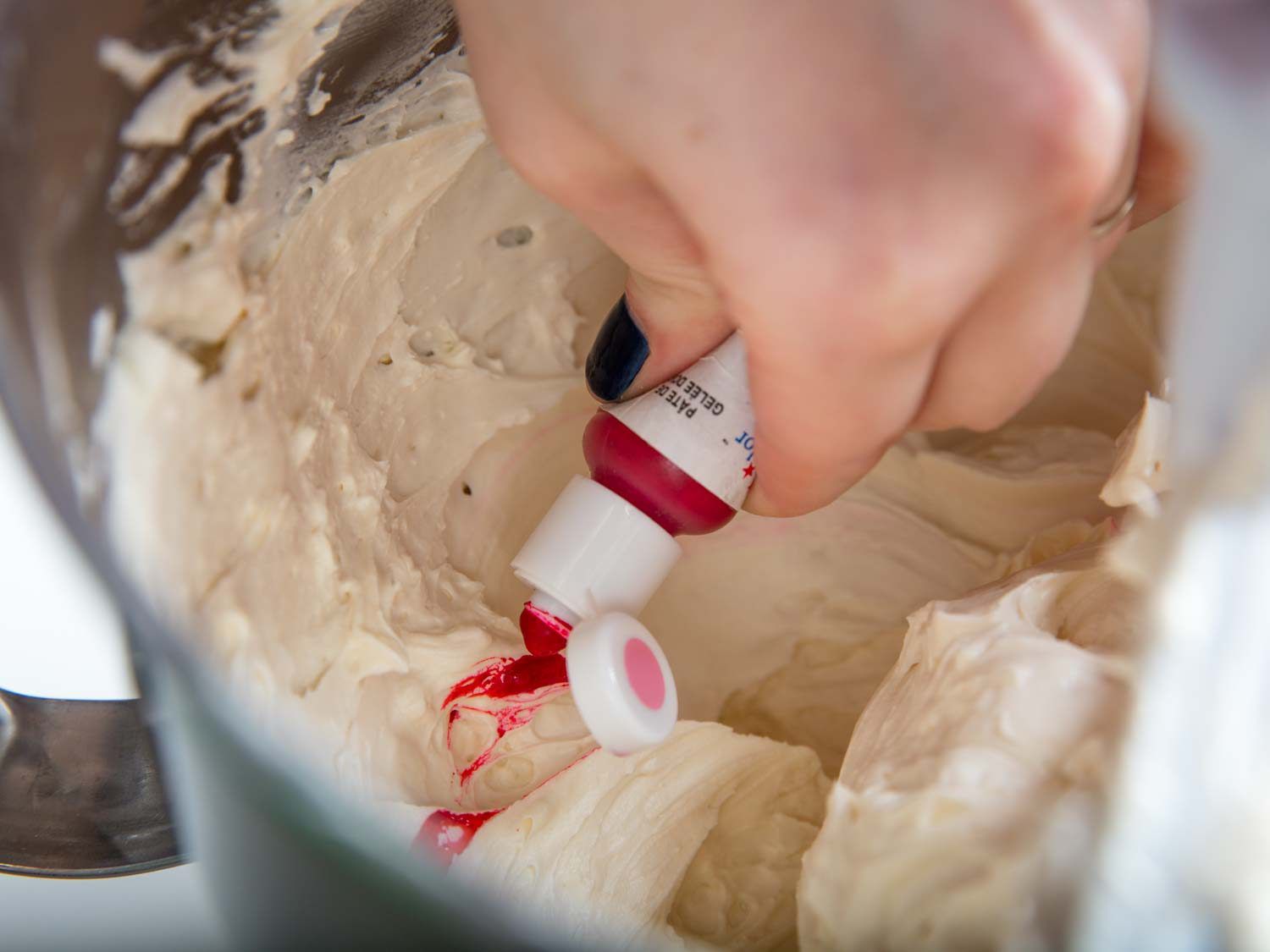 Adding pink gel paste to whipped buttercream.