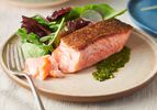 Crispy pan-seared salmon fillet served on a plate with greens