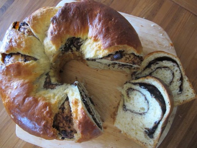 Overhead view of a tube-shaped no-knead chocolate babka. Several slices have been cut to show the swirled filling cross section.