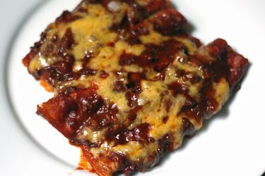 A plate of Tex-Mex cheese enchiladas covered in red chile gravy and a melted cheese 