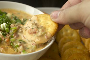 Dipping a Ritz cracker into a bowl of Gooey Cheeseburger Dip