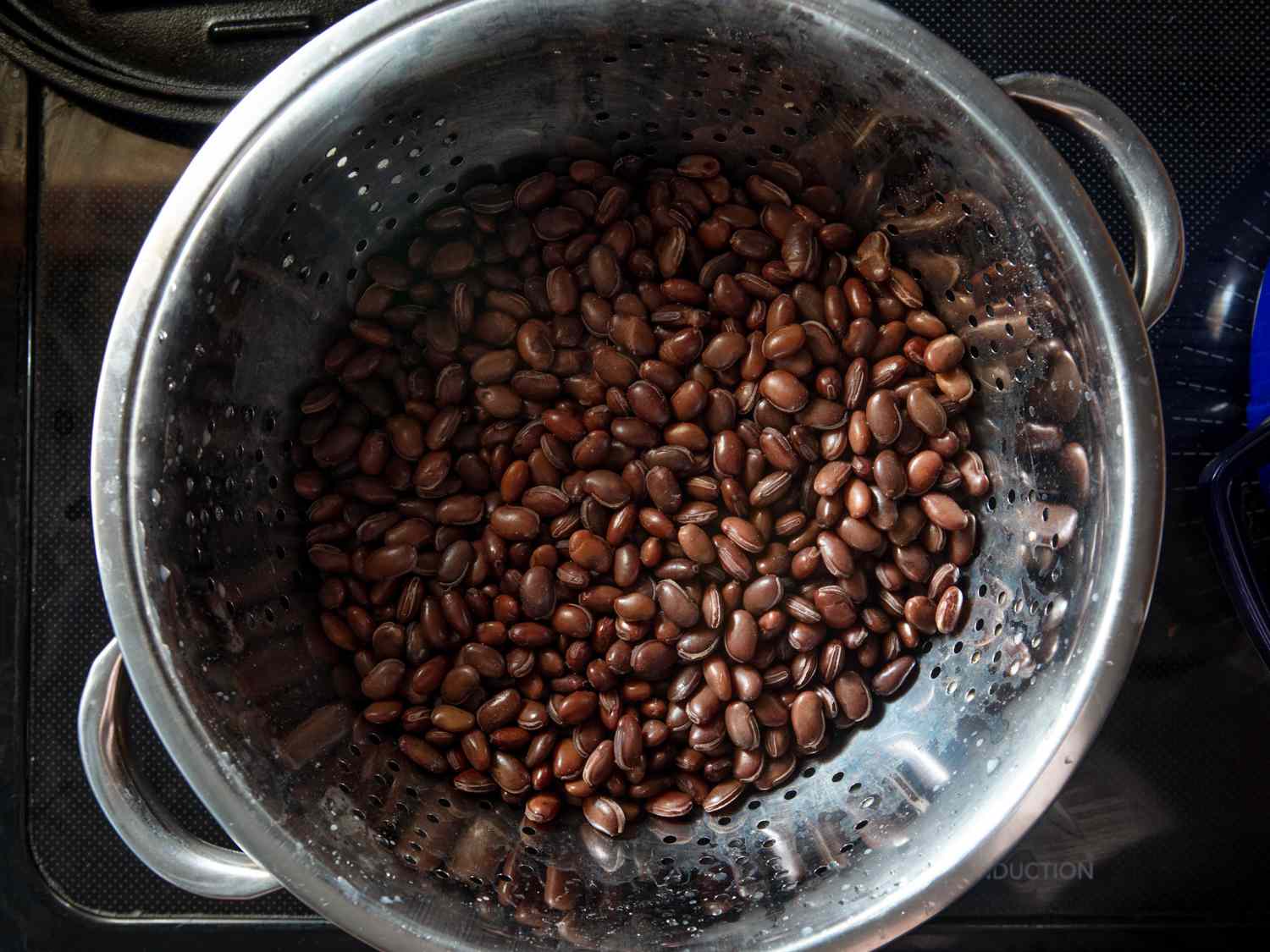 njahi beans strained from their cooking liquid over a pot to reserve the liquid