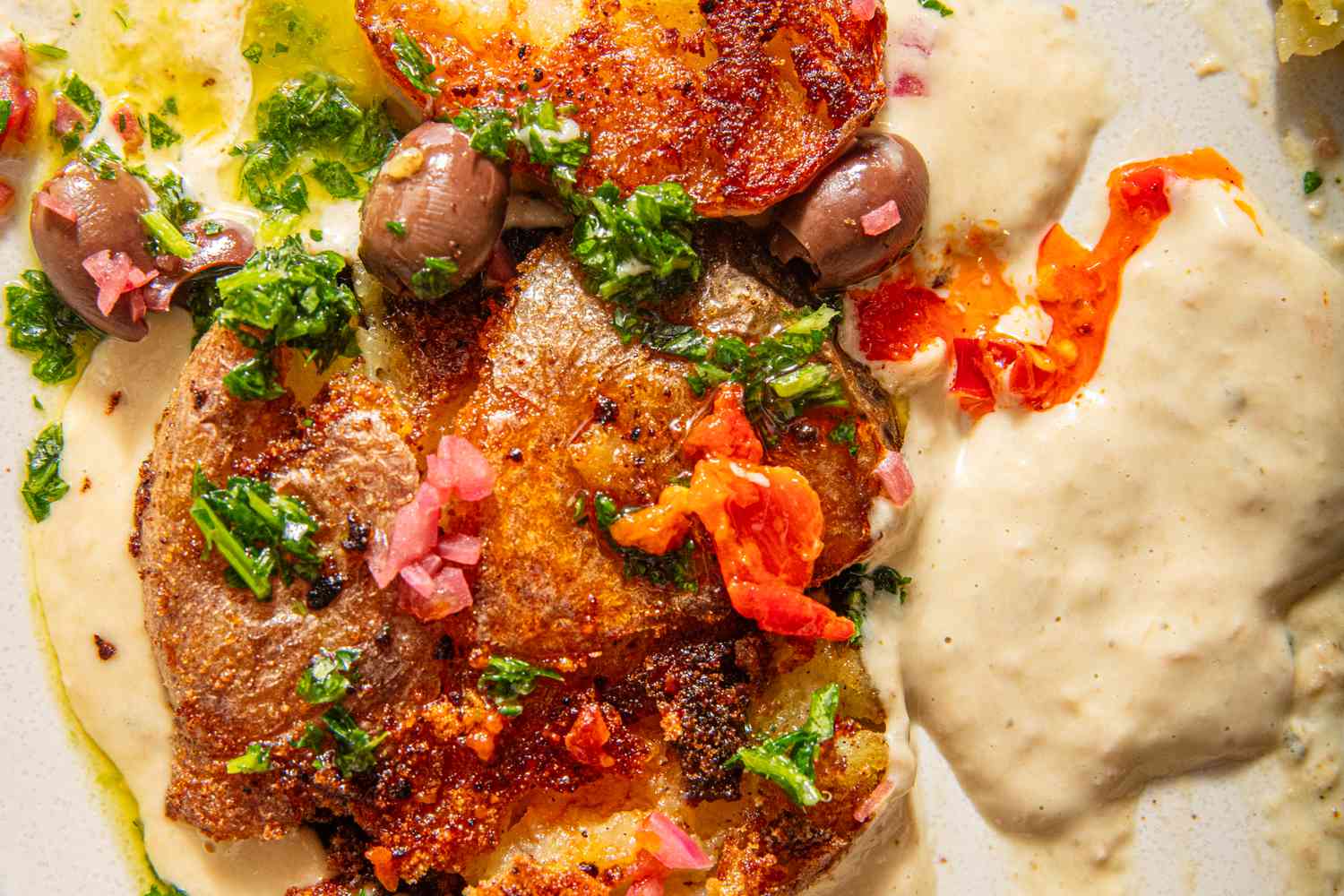 Smashed potatoes with sauce, herbs, and garnish