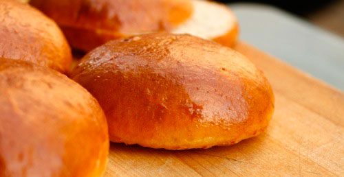 Freshly made hamburger buns on a cutting board. 