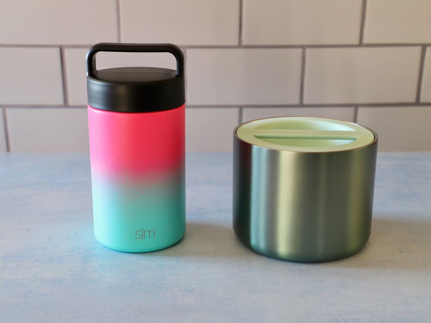 a narrow tall food thermos next to a short, wide one. 