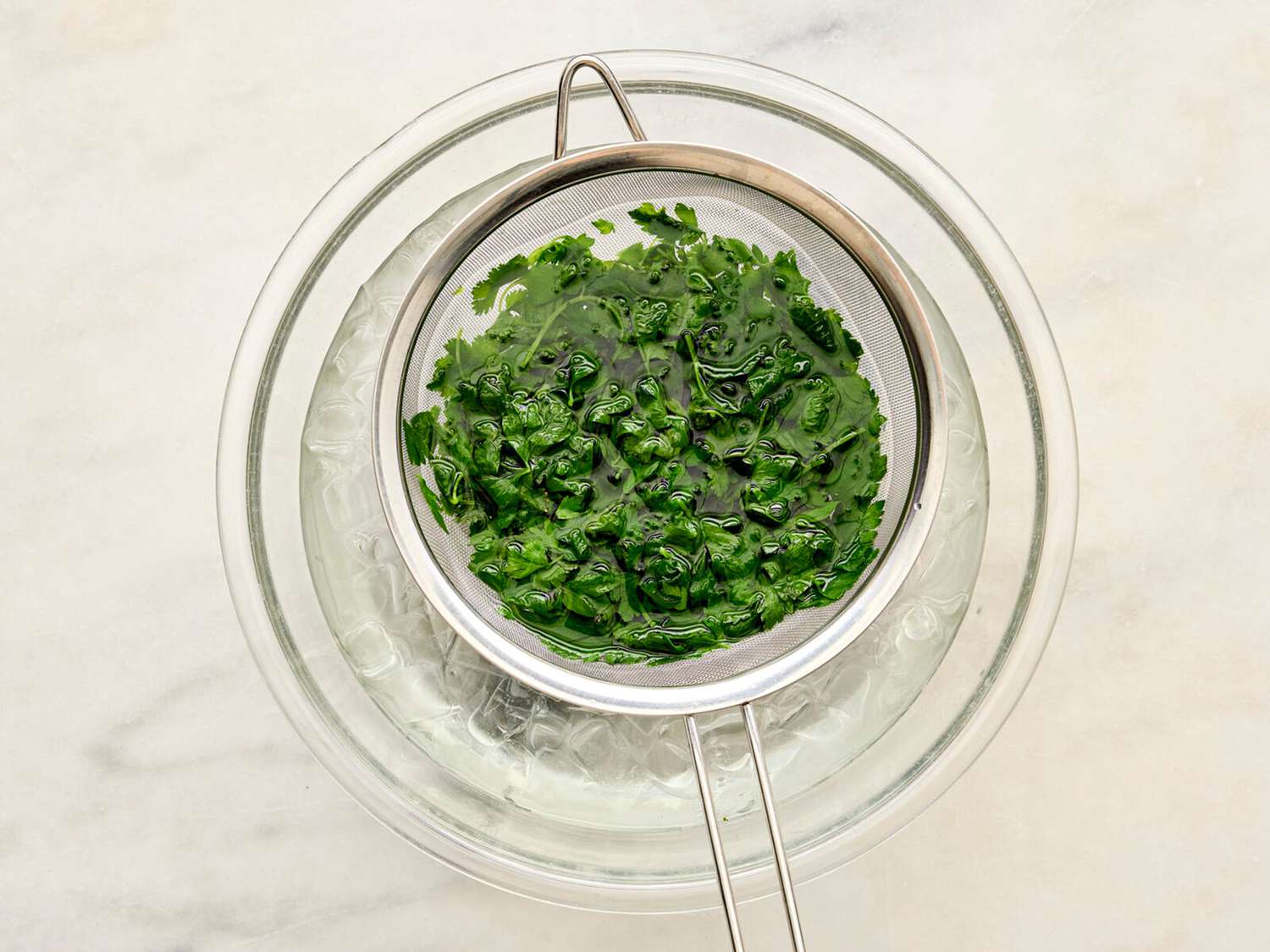 Cilantro and Parsley in a fine-mesh sieve dipped in water. 
