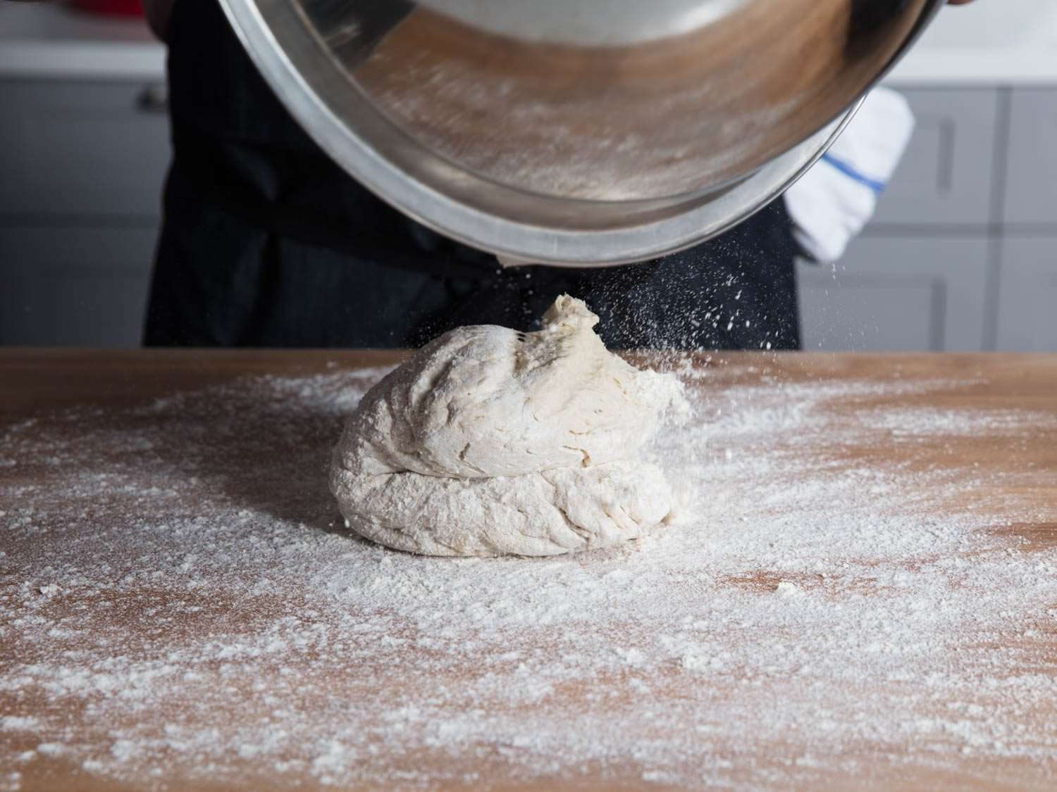 Dough being transferred from bowl to work surface after overnight proof