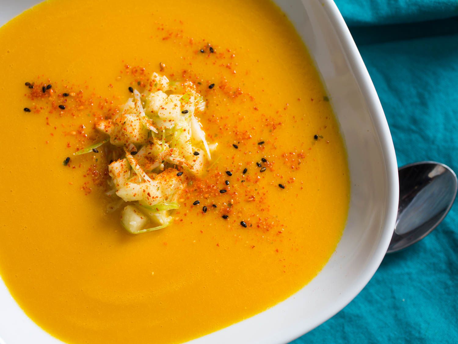A finished serving of miso-squash soup with a mound of the apple-scallion garnish placed in the center of the bowl and light sprinkling of shichimi togarashi.