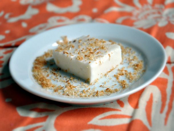 A square of haupia, served on a small plate and sprinkled with toasted coconut.