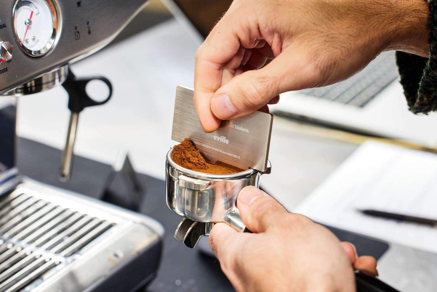 A person pushing off the excess grounded coffee that will be used in the Breville Barista Express Impress