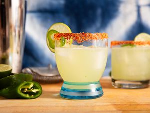 A spicy margarita cocktail garnished with a tajin rim and lime