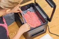 A bag of ground meat is vacuum sealed using the Anova Precision Chamber Vacuum Sealer