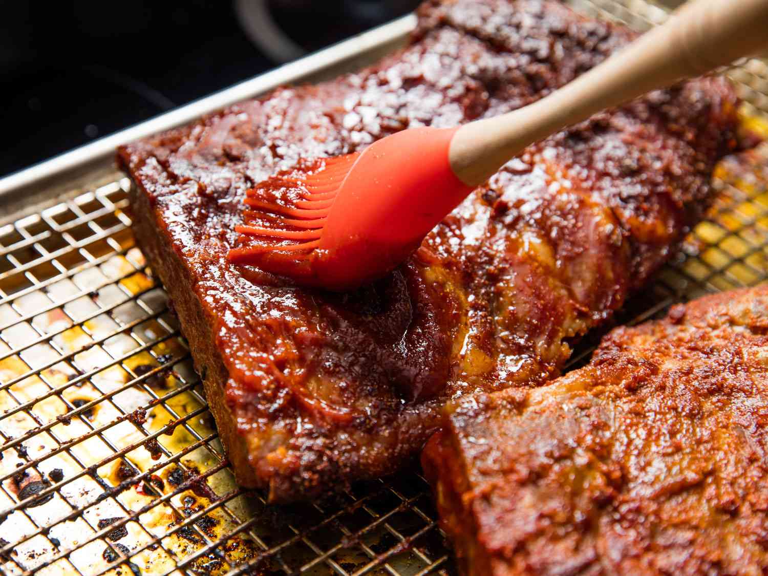 Brushing sauce onto cooked ribs