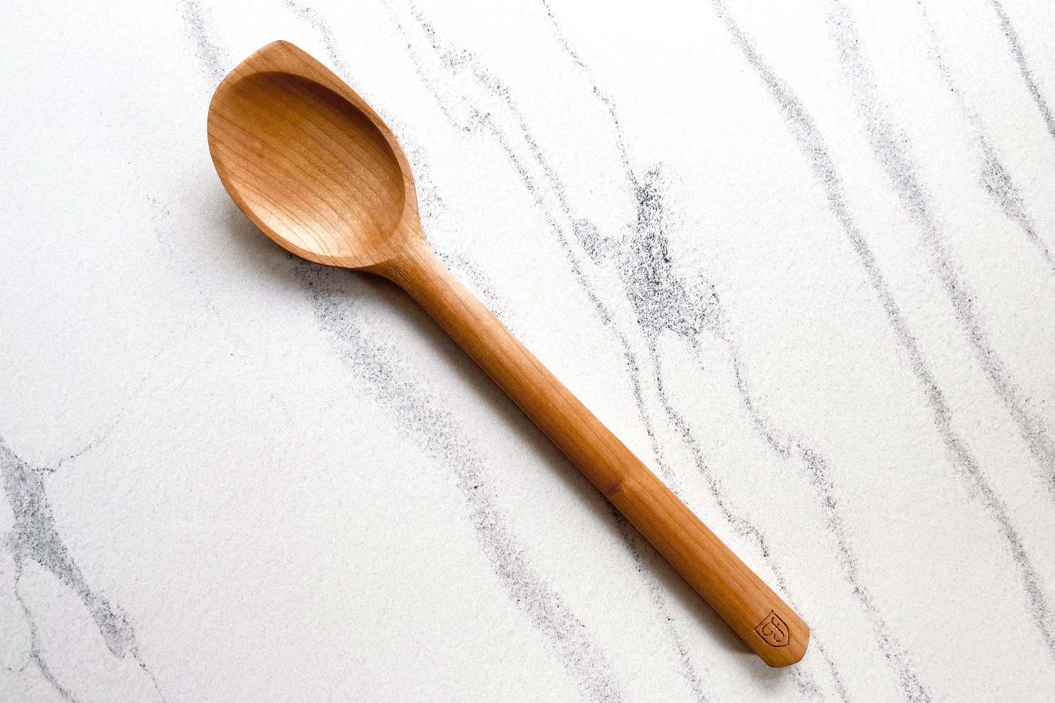 A Field Company Cherry Wood Spoon lies on a marbled surface