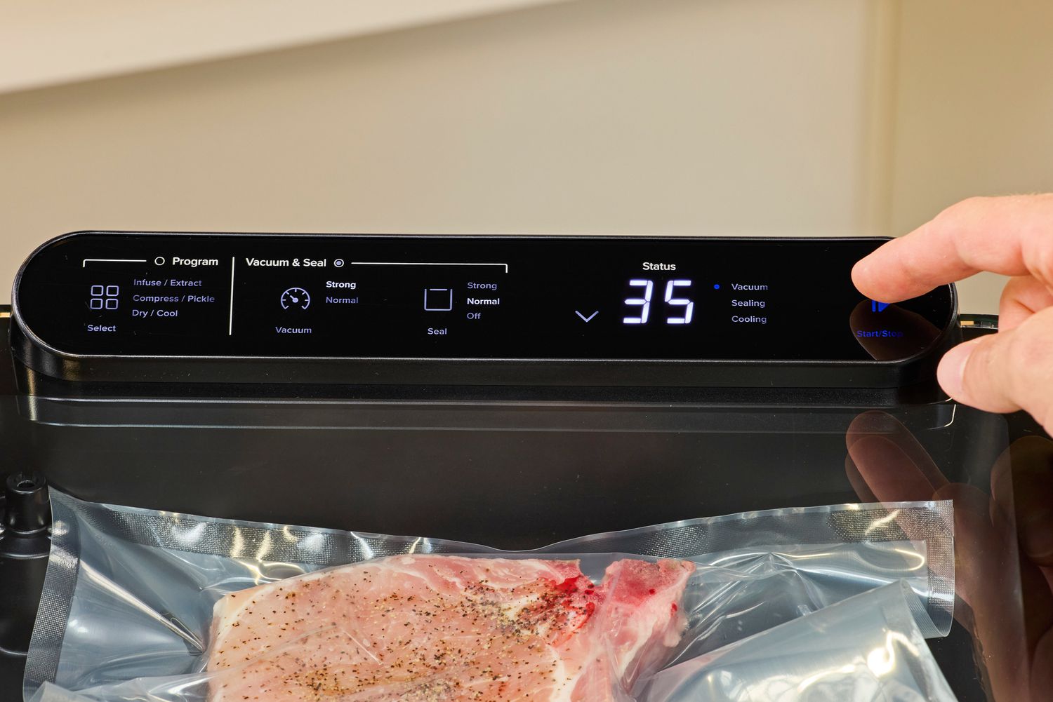 A person presses a button on the Anova Precision Chamber Vacuum Sealer