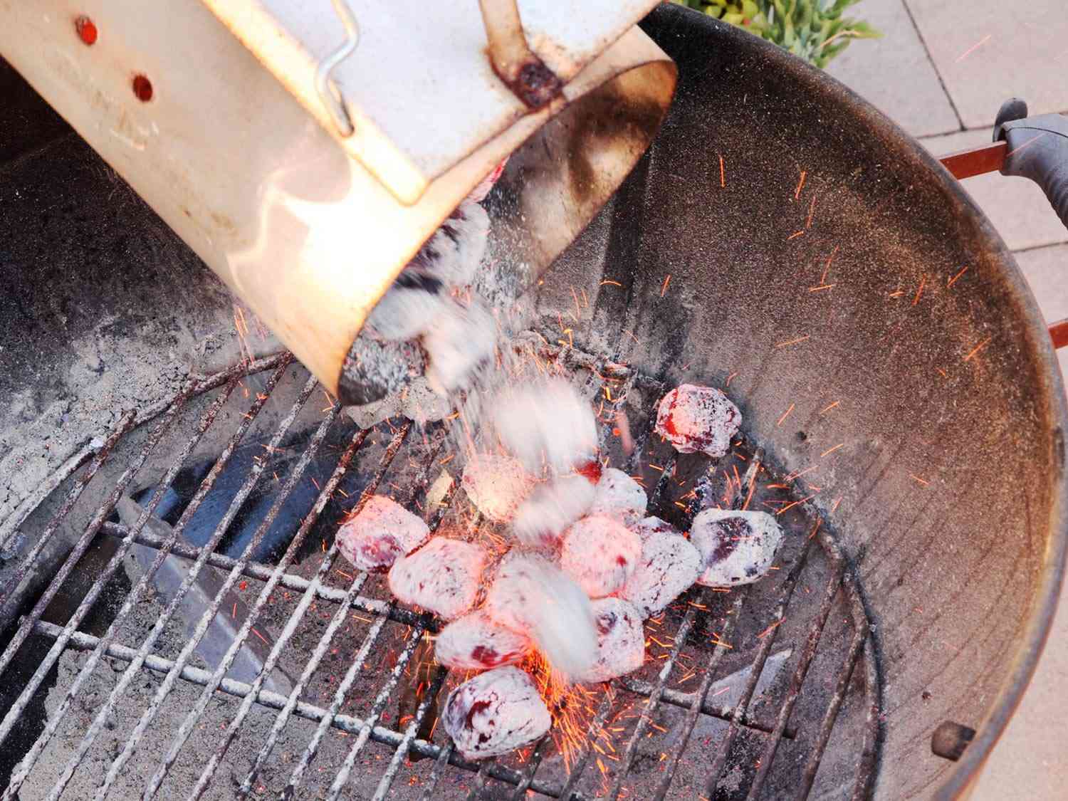 Pouring lit charcoal onto a grill grate