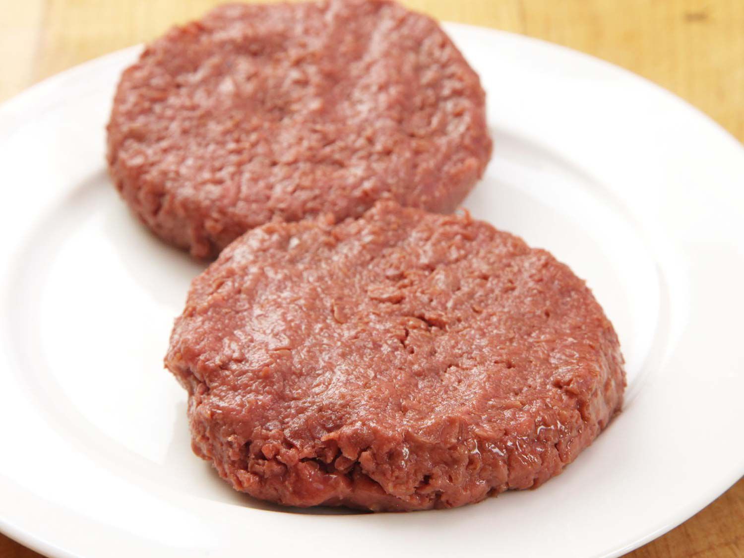 Two uncooked patties of Beyond Meat burger on a plate.