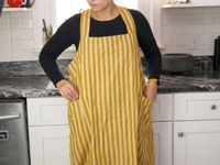 a person pulling a thermometer out of the pocket on the minna apron