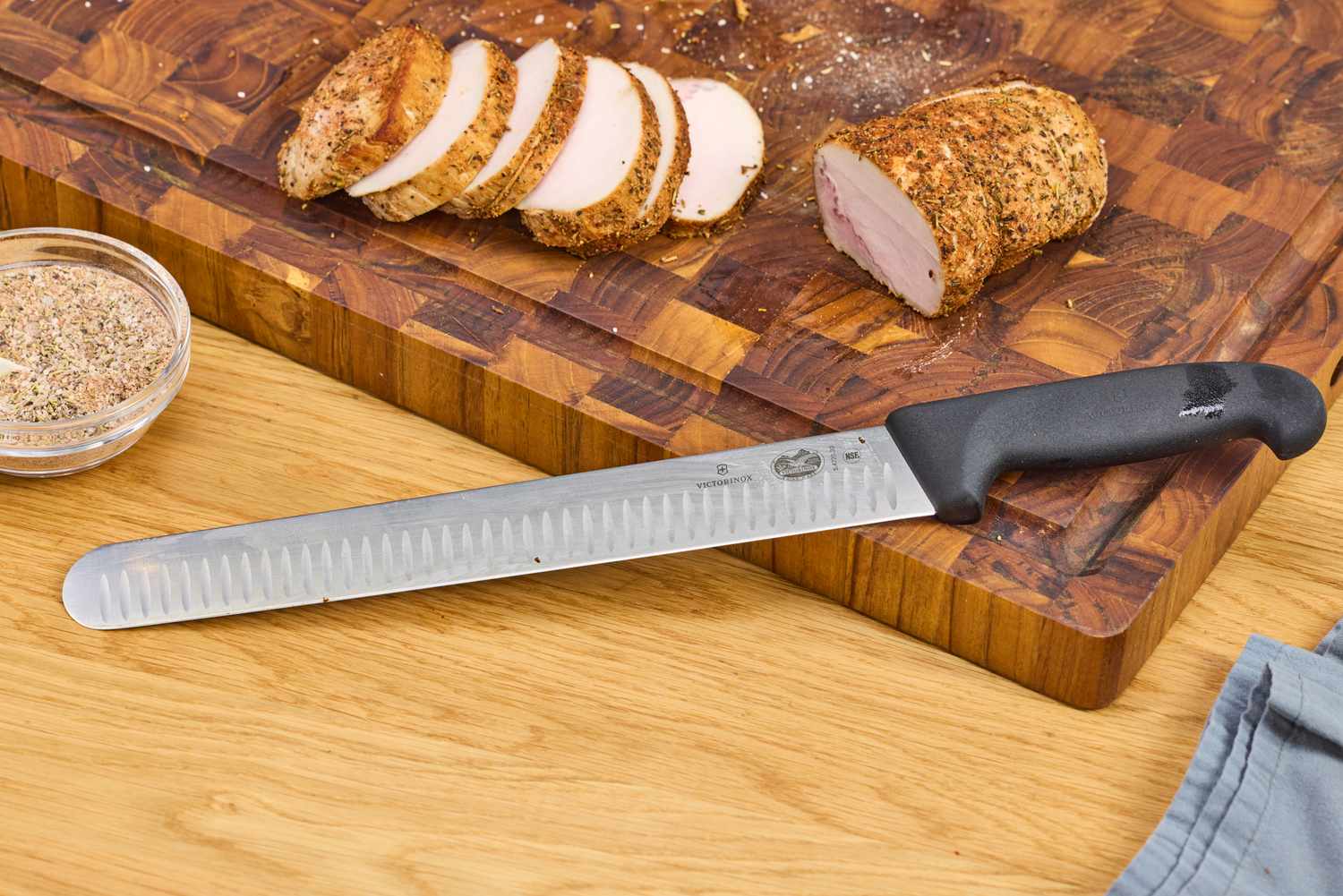 The Victorinox Fibrox Pro 12-Inch Slicing Knife with Granton Blade rests on a cutting board
