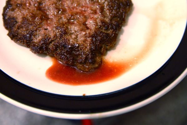 A cooked patty and its juices released while resting. 