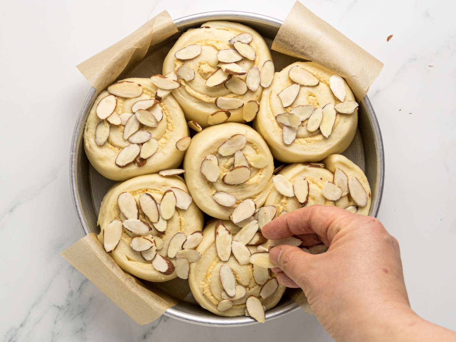 Sprinkling rolls in pan on white marble surface 