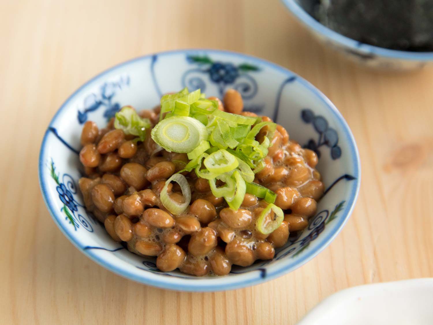 Natto in a ceramic bowl, topped with sliced scallions