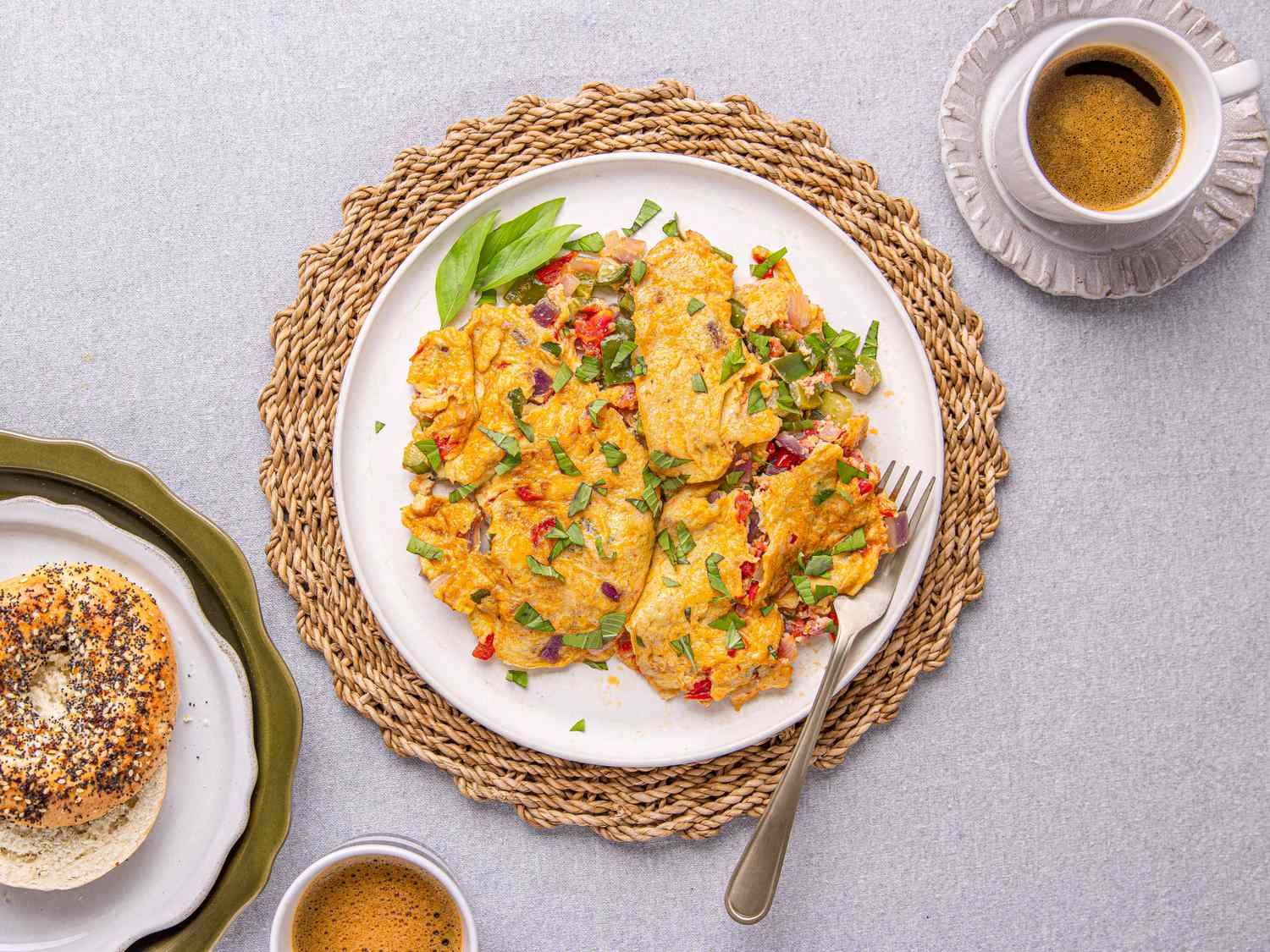 A prepared plate of Nigerian omelet with a fork on a woven placemat served with coffee and a bagel