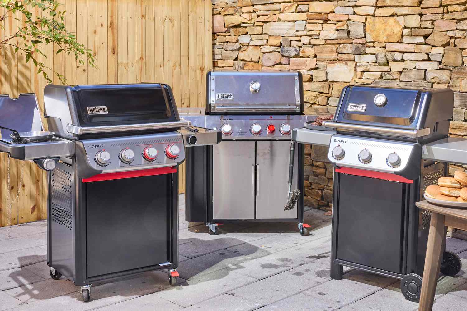 Three gas grills on an outdoor patio.