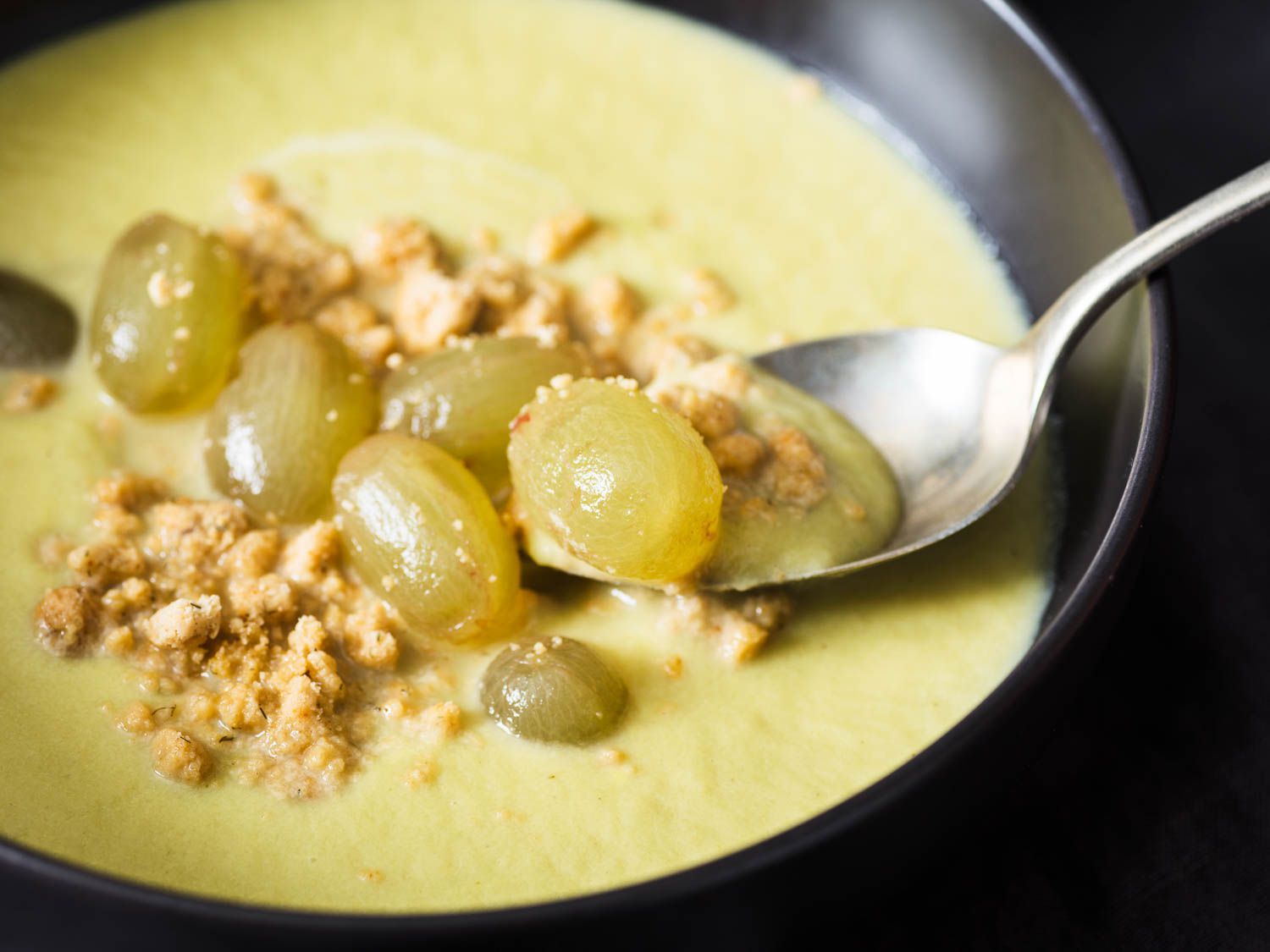 A spoon holds a bite of the plated soup up for the camera.
