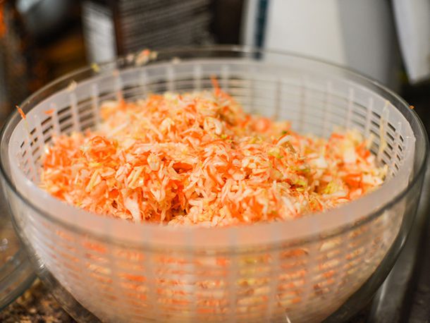 A bowl of grated vegetables for coleslaw after draining, in the bowl of a salad spinner for drying.