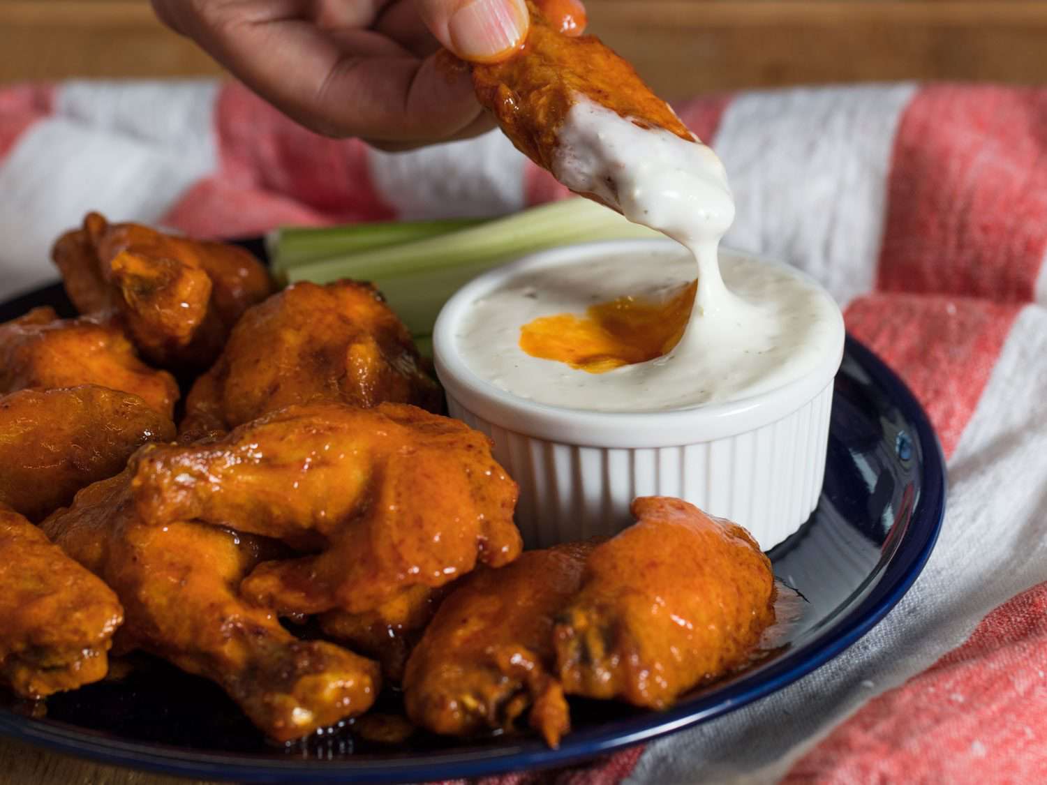 Sous vide buffalo chicken wings being dipped in blue cheese sauce.