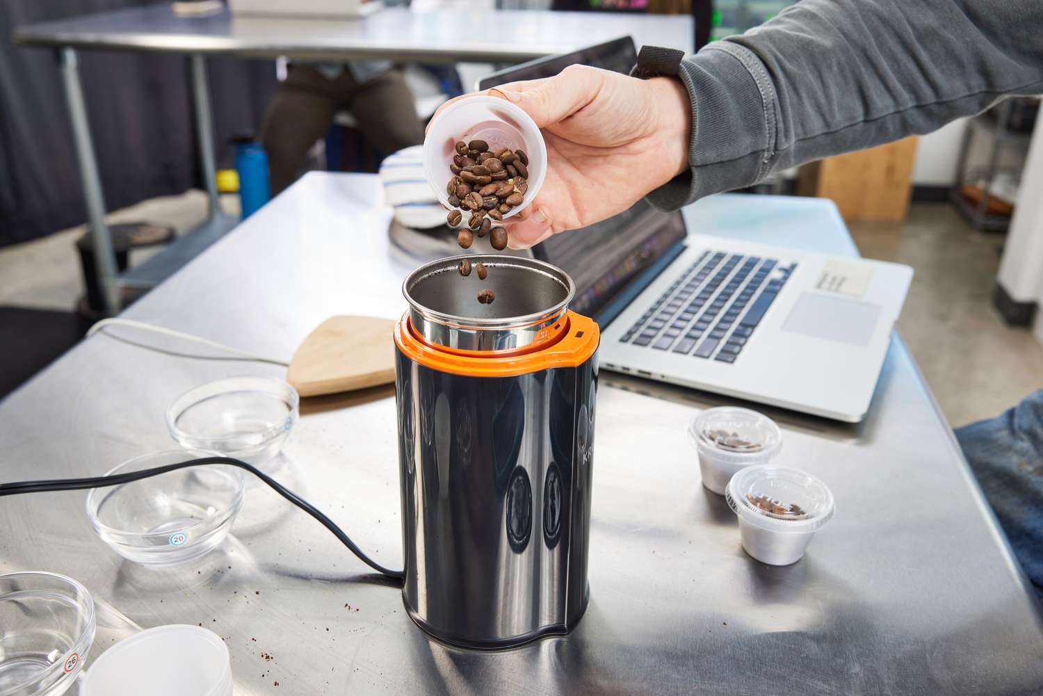 A person pouring coffee beans into a blade grinder.