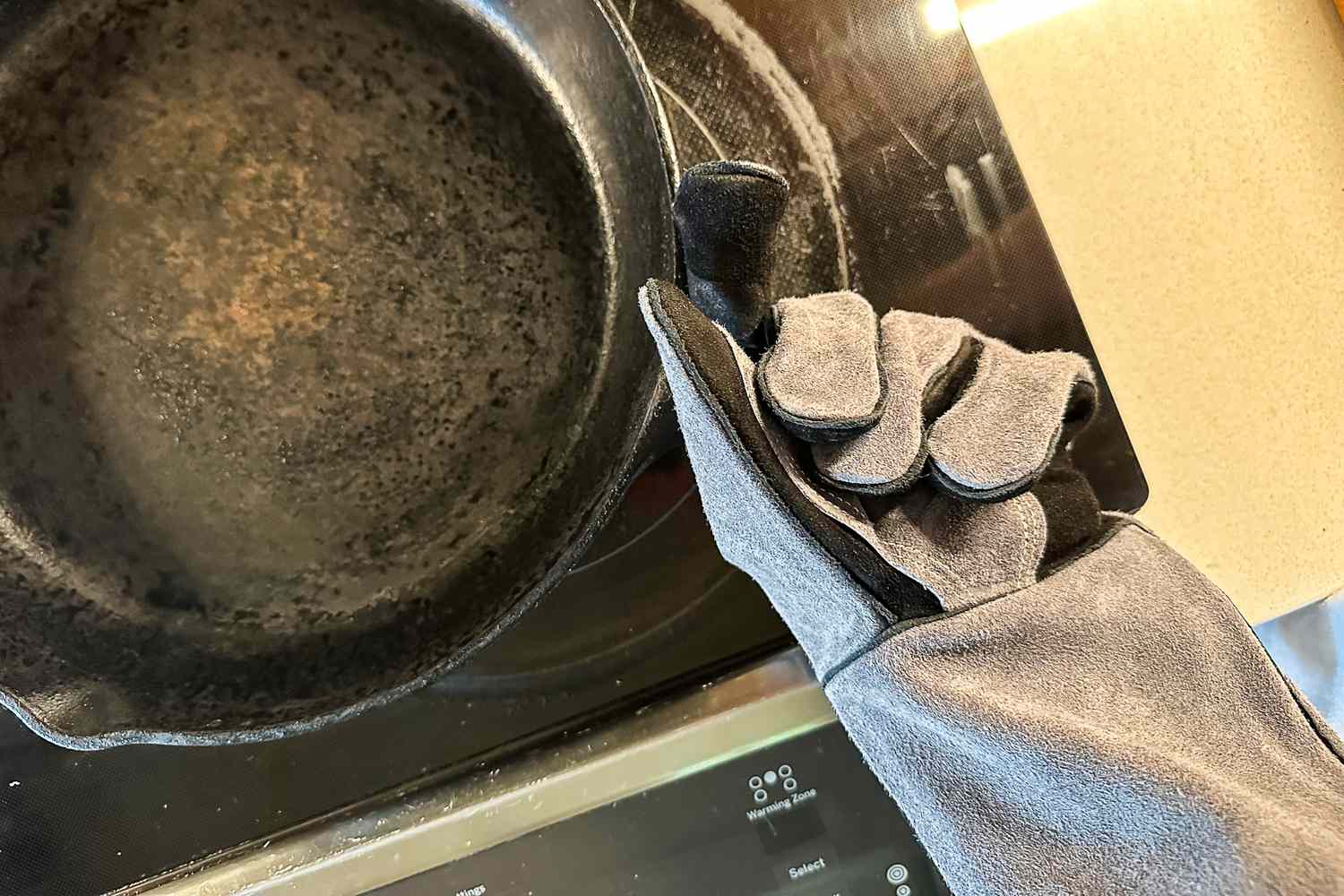 A person holds a cast iron pan while wearing the Breeo Fire Pit Glove