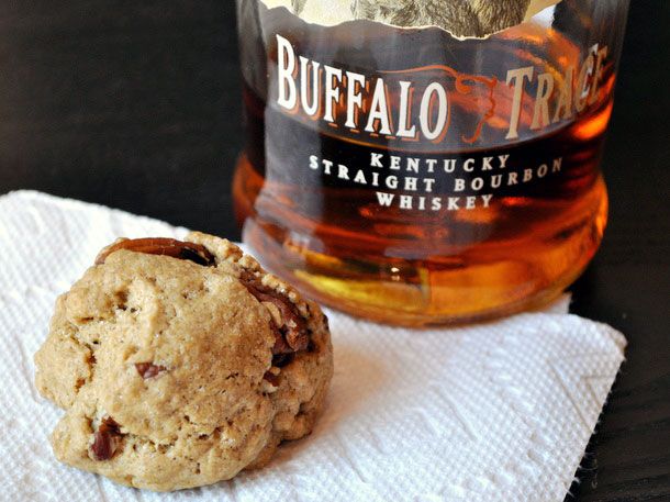 Closeup of a brown butter bourbon cookie next to a nearly empty bottle of Buffalo Trace Kentucky straight bourbon whiskey.