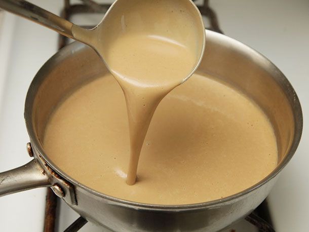 The blended soup is returned to the saucepan. A ladle pours some of the soup back into pan, showing off its viscosity.