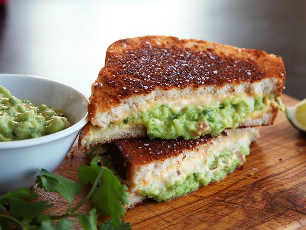 Cross-section view of two halves of a grilled cheese sandwich with guacamole.