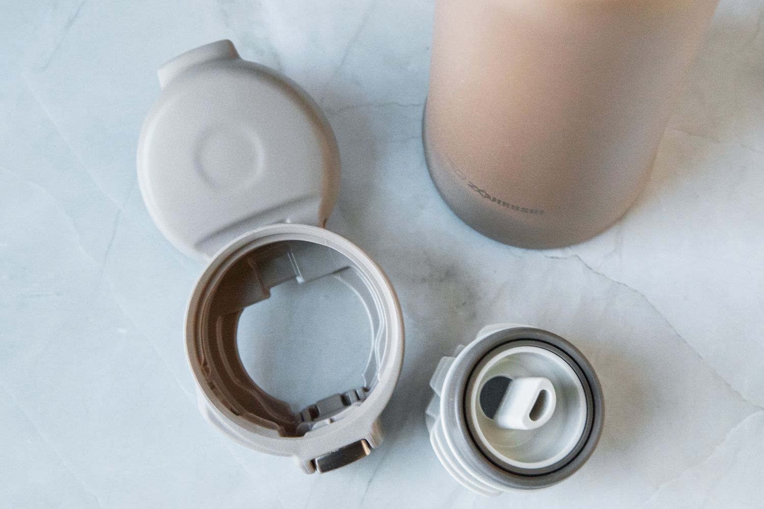 The Zojirushi travel mug's lid taken apart into two pieces.