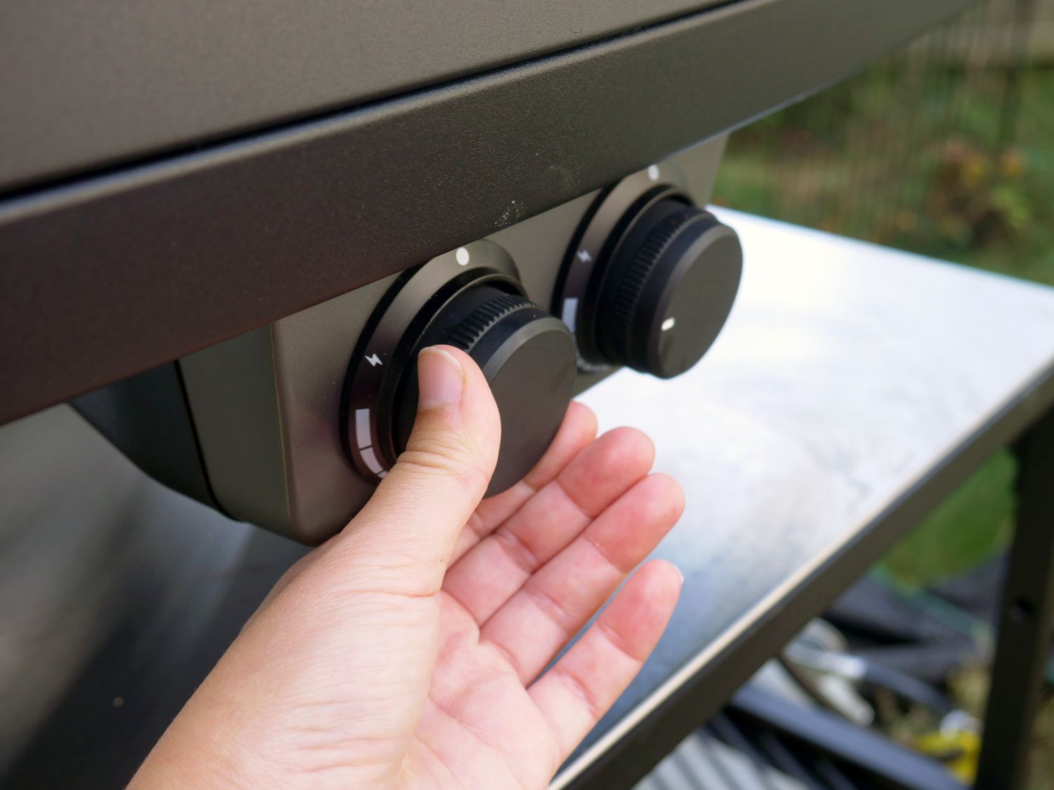 a person adjusting the burners on the side of the pizza oven