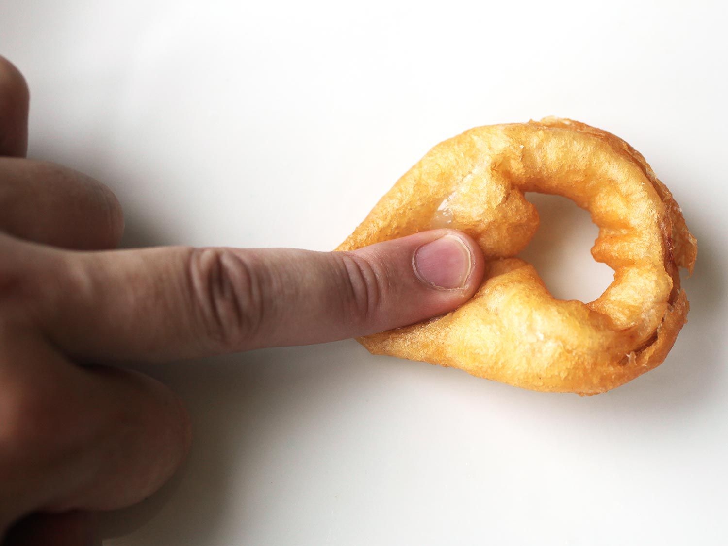 Author pushes on a squishy, over-battered onion with their middle finger.