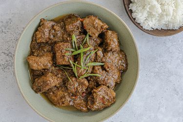 Bikol Express in light green bowl next to a bowl of rice