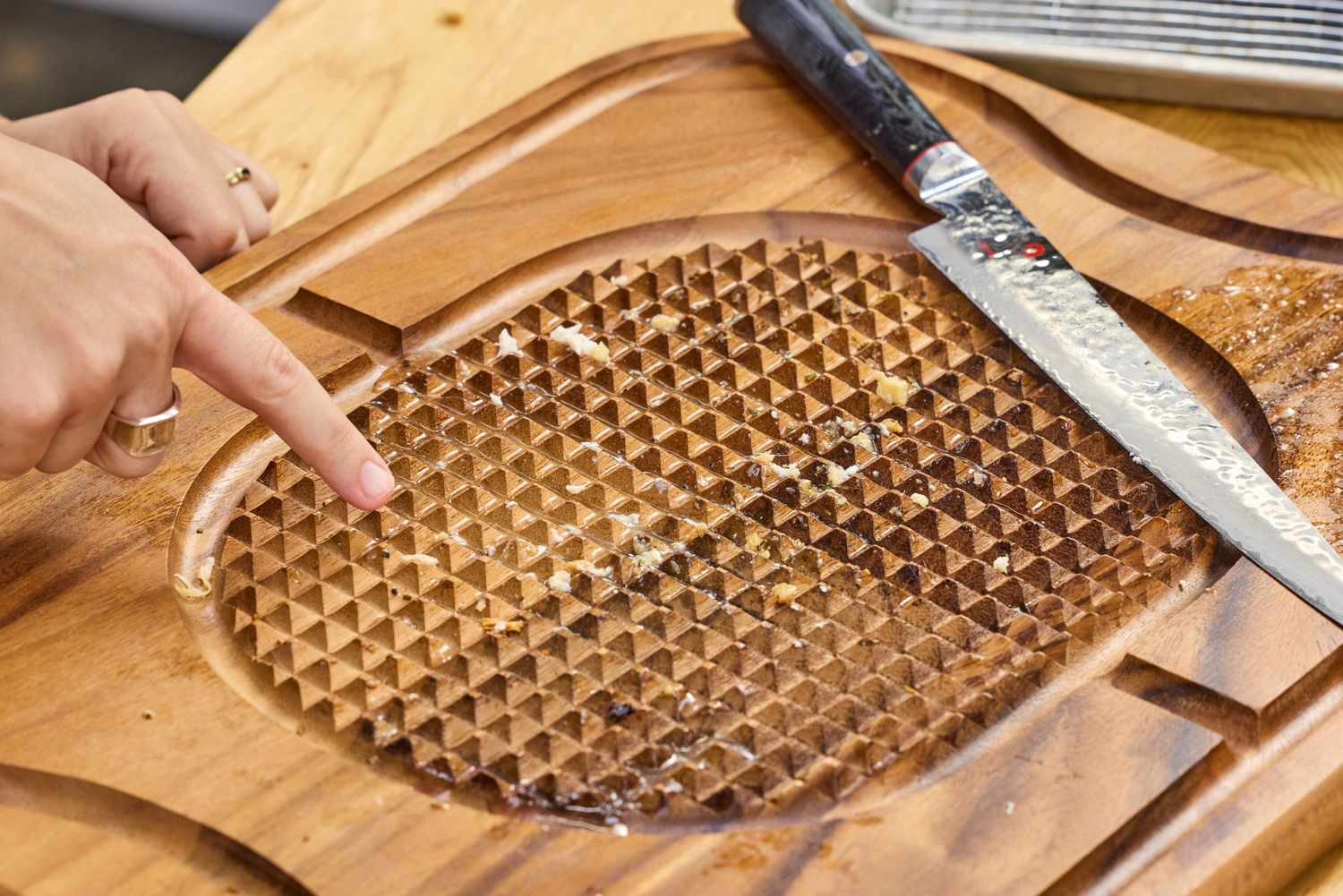 A Lipper International Acacia Cutting Board with Grid Grip next to a knife