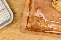 The Boardsmith Maple End-Grain Cutting Board with juices and crumbs next to a metal tray