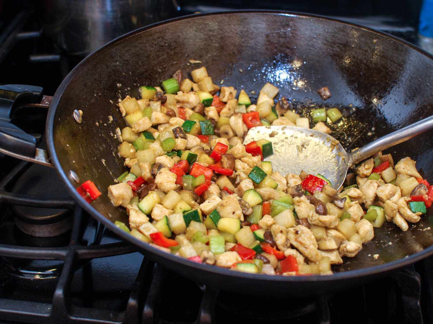 A wok containing diced vegetables and chicken. 