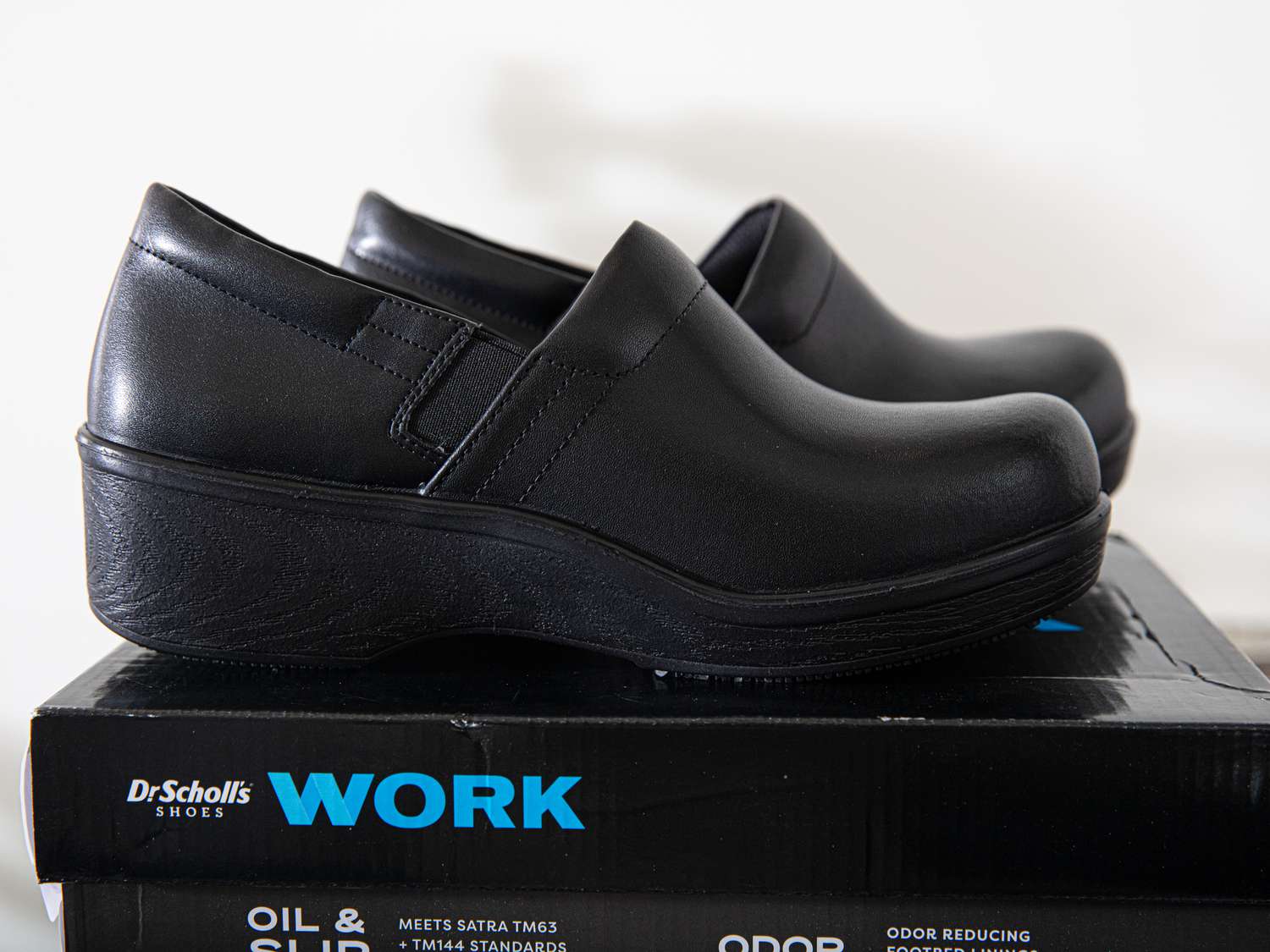A pair of black kitchen clogs on top of a shoe box.