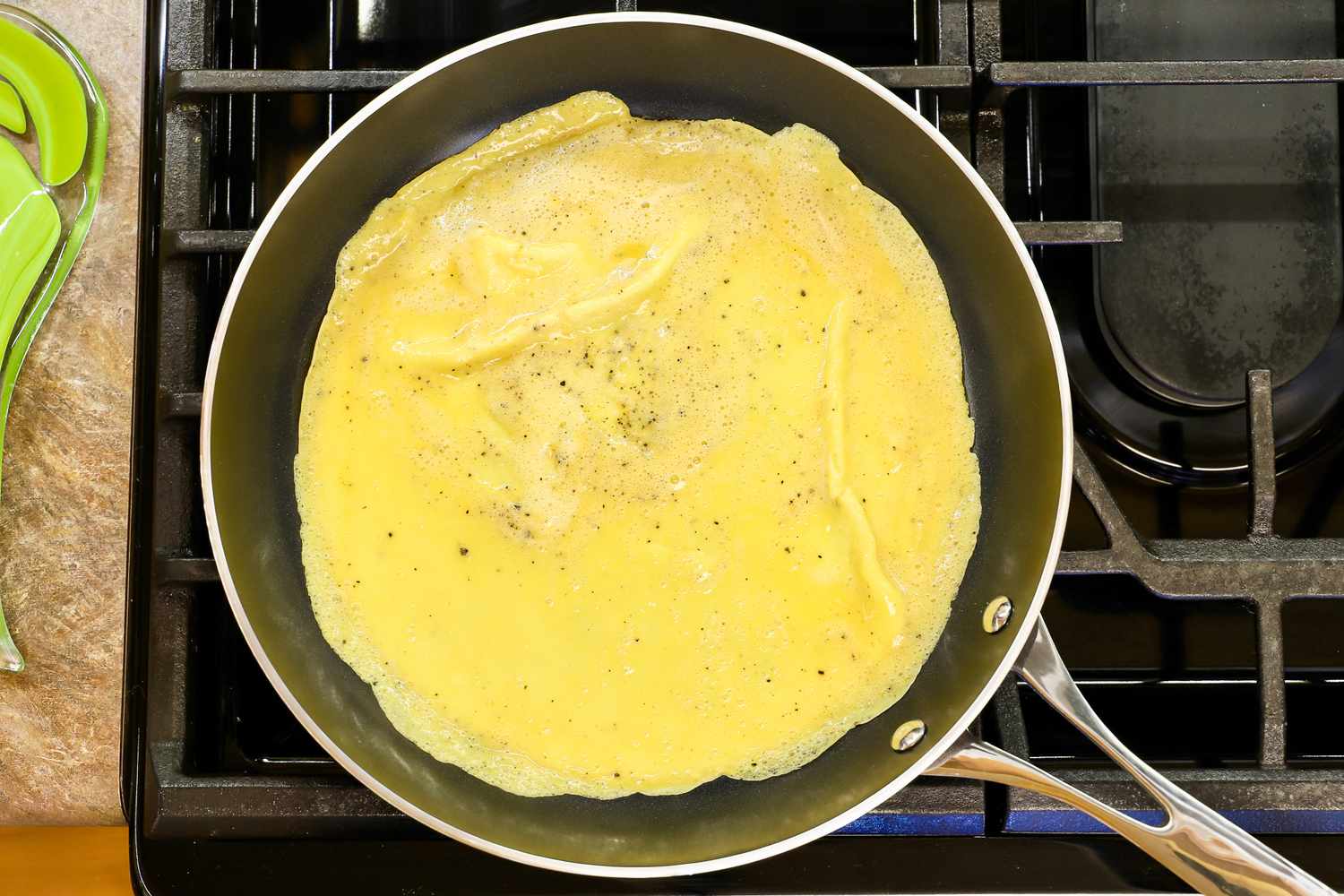 A Kyocera nonstick ceramic skillet on a stove with an omelet being cooked inside